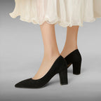 ZOFIA ATELIER black suede pointed toe pumps with a chunky heel and a flowing white skirt.