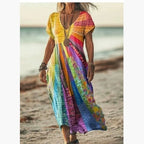 ZOFIA ATELIER Gabrysia floral V-neck midi dress with short sleeves in a colorful patchwork print, flowing silhouette, beach setting.