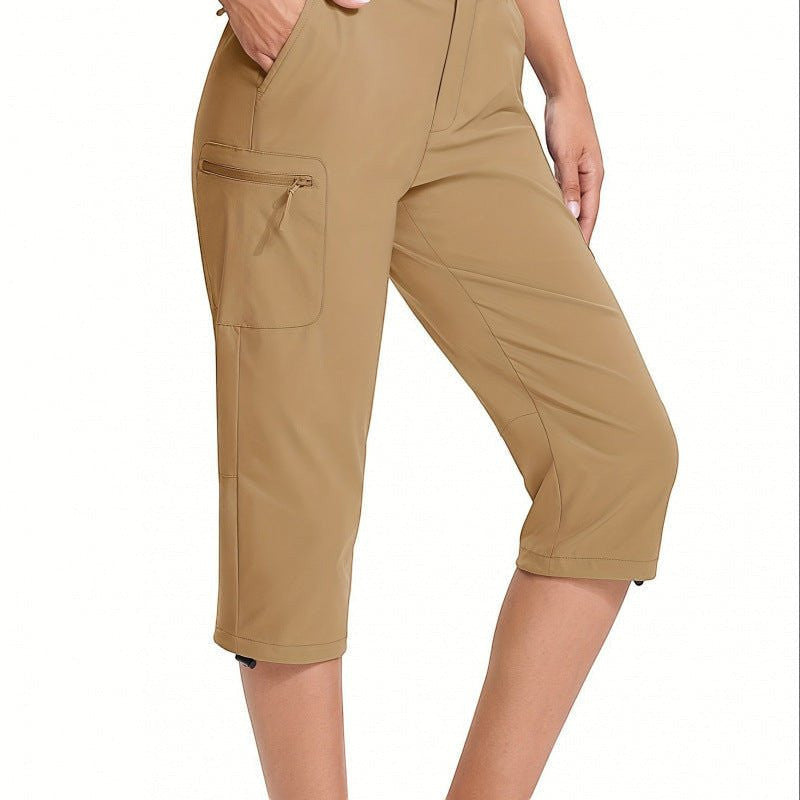 ZOFIA ATELIER MAGDA Asymmetric Waterproof Pants in Khaki. Lightweight, seven-quarter length, wide-leg flared pants with zippered cargo pocket.