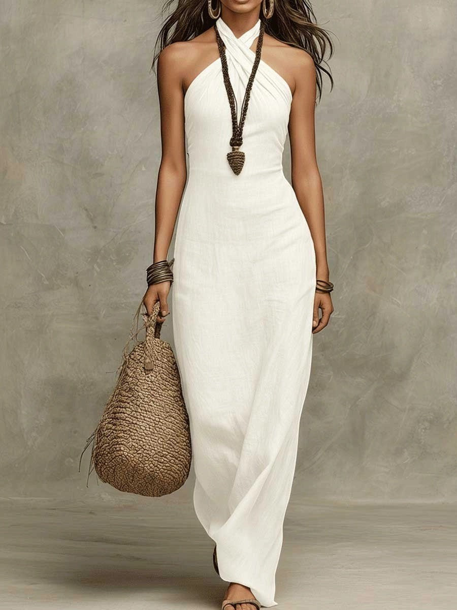 ZOFIA ATELIER white linen blend maxi dress with halter cross V-neckline and flowing skirt. Model holds a woven bag.